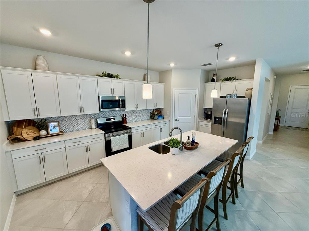 10852 Sun Drop Street Venice, FL 34293 - Photo 6 of 15 a kitchen with a dining table cabinets appliances and wooden cabinets