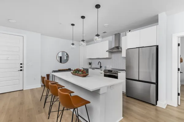 a kitchen with stainless steel appliances granite countertop a sink a stove a refrigerator and island with wooden floor