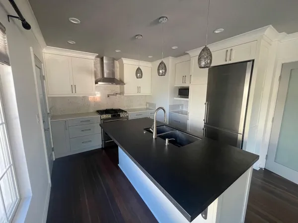 a kitchen with stainless steel appliances granite countertop a refrigerator a sink a stove and a refrigerator with wooden floor