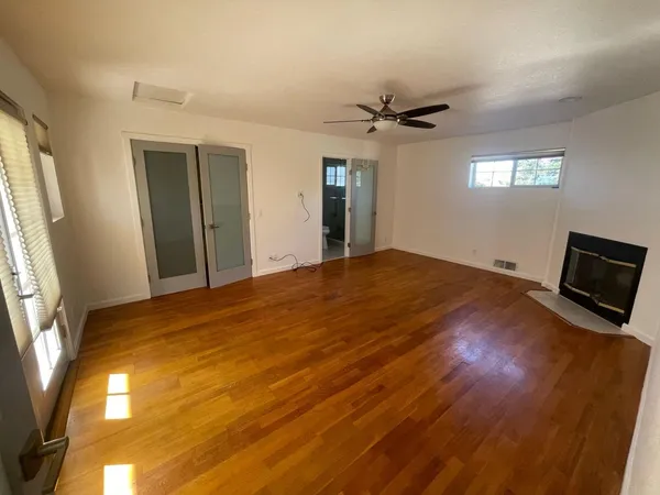 a view of empty room with wooden floor and fan