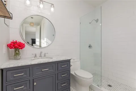 a bathroom with a toilet sink vanity granite and mirror