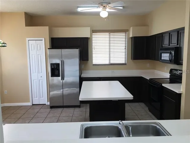 a kitchen with kitchen island granite countertop stainless steel appliances a sink stove and refrigerator