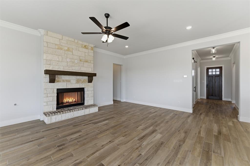 814 Vly Rdg Road Van Alstyne, TX 75495 - Photo 13 of 24 a view of a livingroom with wooden floor a ceiling fan and a fireplace