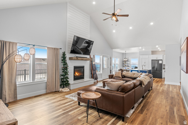 1343 North Trapper Loop Garden City, UT 84028 - Photo 15 of 56 Living area with a ceiling fan, a large fireplace, a chandelier, light wood-style flooring, and vaulted ceiling