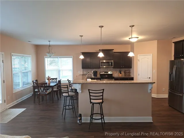 a kitchen with granite countertop a table chairs microwave and sink
