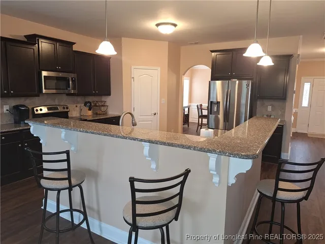 a kitchen with granite countertop a sink a counter space appliances and cabinets