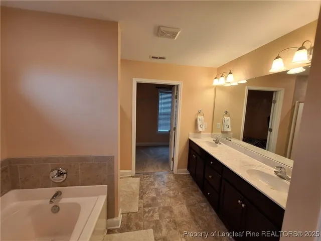 a spacious bathroom with a double vanity sink a mirror and a shower