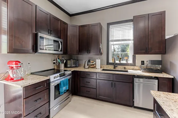 a kitchen with stainless steel appliances granite countertop a sink stove refrigerator and cabinets