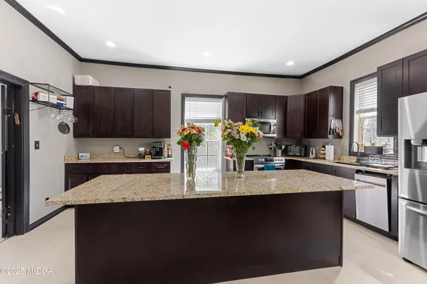 a kitchen with kitchen island granite countertop a sink stove and refrigerator