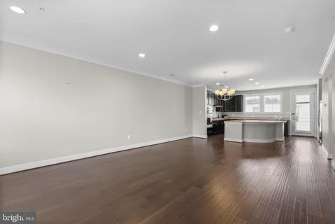 an empty room with wooden floor chandelier and windows
