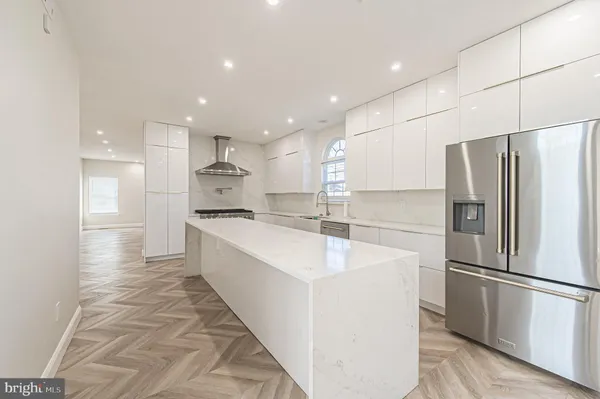 a large white kitchen with a stove a sink a refrigerator and a fireplace