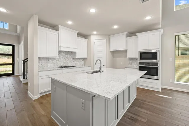 a kitchen with a sink a counter top space stainless steel appliances and cabinets