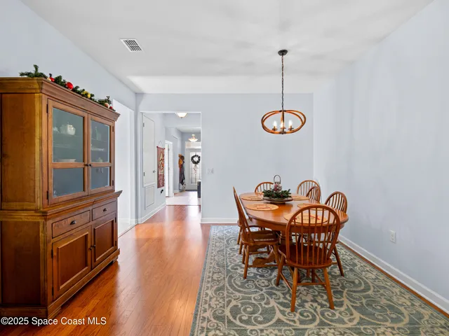 a view of a dining room with furniture a chandelier and wooden floor