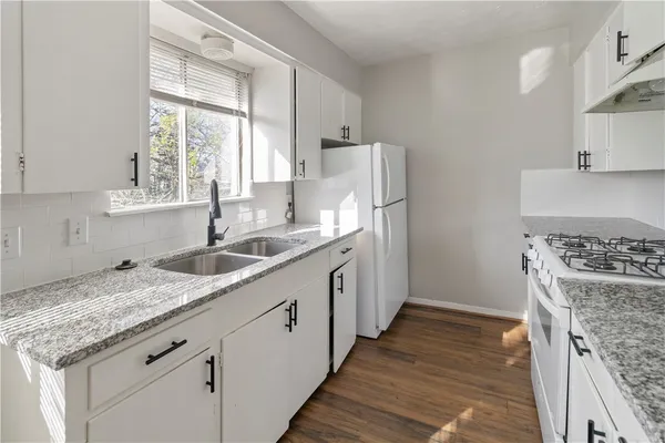 a kitchen with granite countertop a sink stove and refrigerator