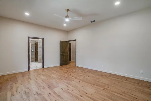 a view of an empty room with wooden floor and closet