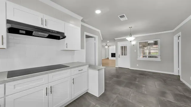 a kitchen with white cabinets and black appliances