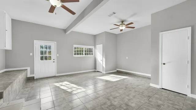 a view of a big room with chandelier fan and windows