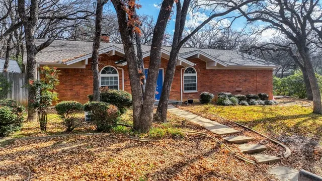 a view of a house with a yard covered with large trees