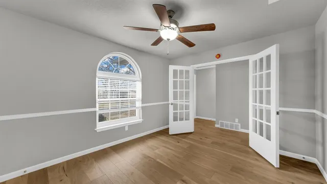 a view of an empty room with a window and wooden floor