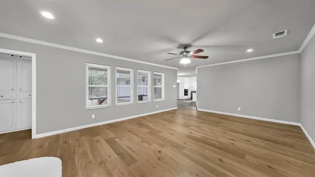 a view of an empty room with a window and wooden floor