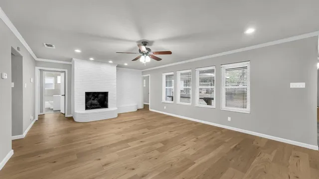 a view of an empty room with a window and wooden floor