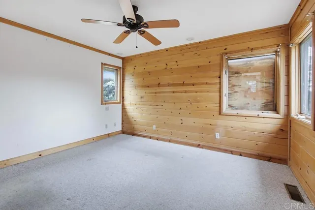 an empty room with windows and fan