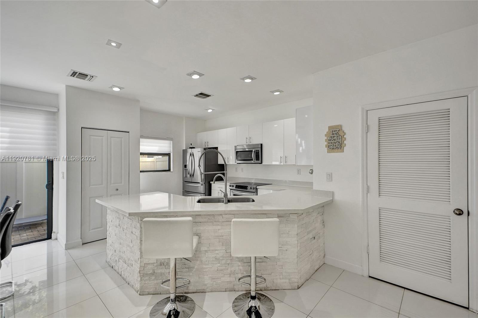 377 Northeast 194th Terrace Miami, FL 33179 - Photo 6 of 19 a dining hall with stainless steel appliances kitchen island granite countertop a sink and a refrigerator