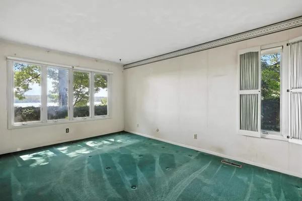 a view of an empty room with window and stairs