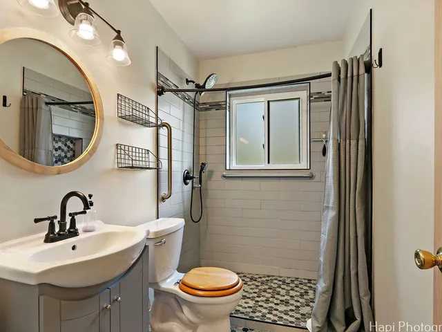 a bathroom with a sink a toilet a mirror and shower