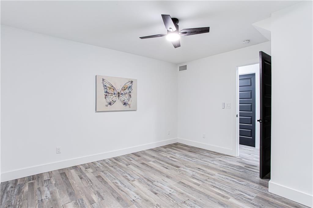 3038 Sutter Court Southwest Snellville, GA 30039 - Photo 14 of 22 an empty room with wooden floor chandelier fan and windows