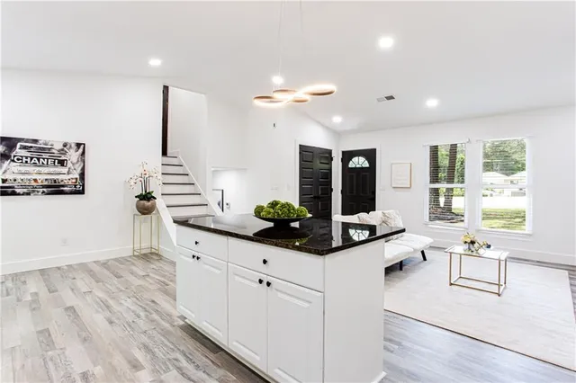 a kitchen with stainless steel appliances a refrigerator a sink a stove and white cabinets