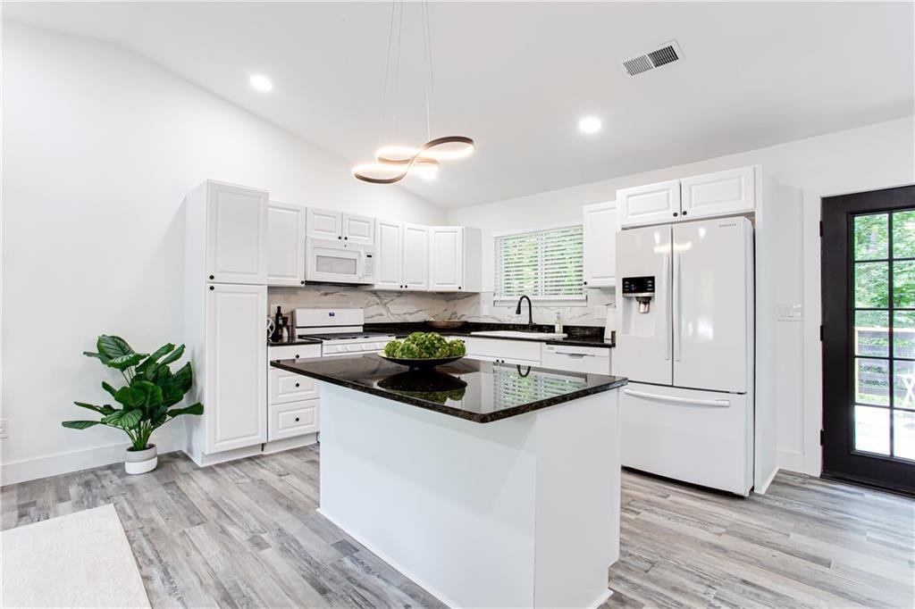 3038 Sutter Court Southwest Snellville, GA 30039 - Photo 5 of 22 a kitchen with stainless steel appliances a refrigerator a sink a stove and white cabinets