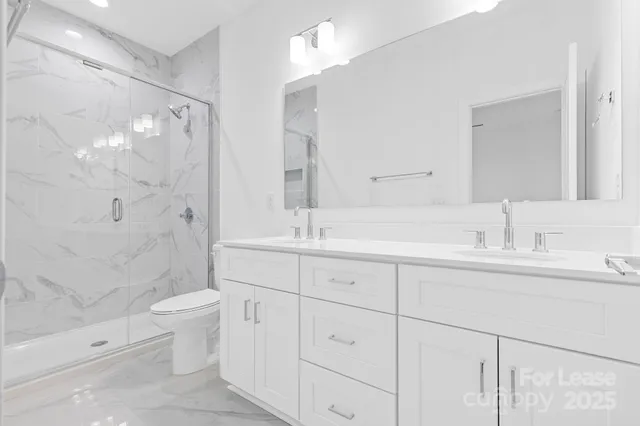 a bathroom with a double vanity sink toilet and shower
