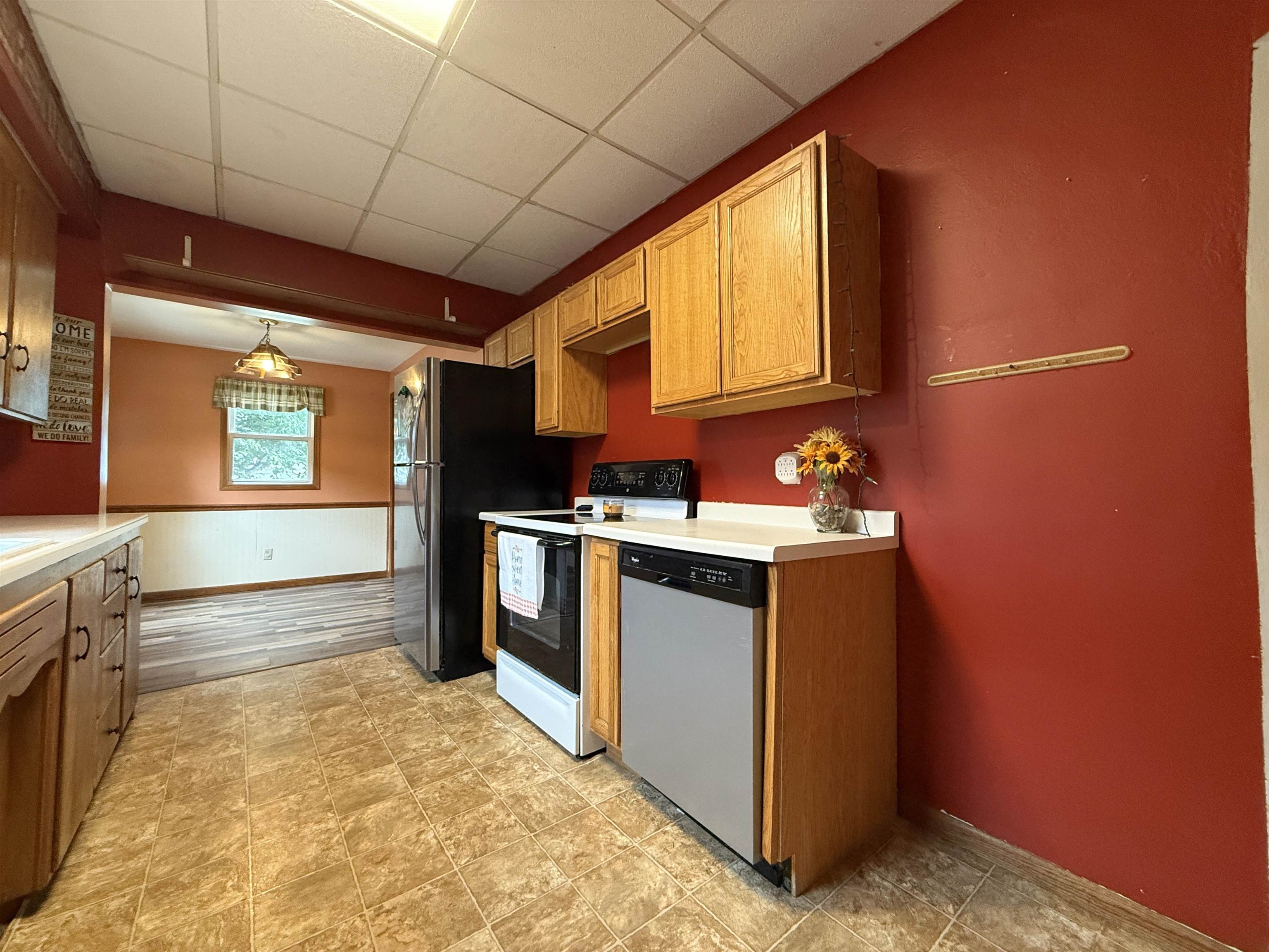 809 16th Street North Virginia, MN 55792 - Photo 18 of 44 Kitchen featuring electric range oven, a drop ceiling, stainless steel dishwasher, light countertops, and wainscoting