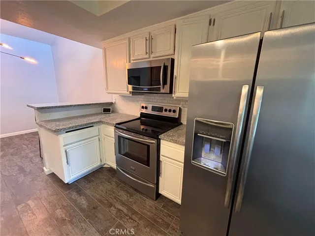 a kitchen with white cabinets and stainless steel appliances