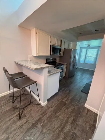 a kitchen with stainless steel appliances granite countertop a table chairs sink and cabinets