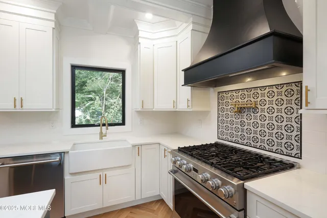 a kitchen with white cabinets appliances and windows