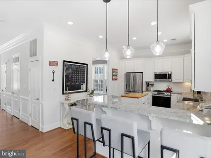 a kitchen with stainless steel appliances kitchen island granite countertop a stove a sink and a refrigerator with wooden floor