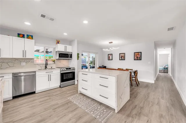 a kitchen with white cabinets stainless steel appliances and wooden floor