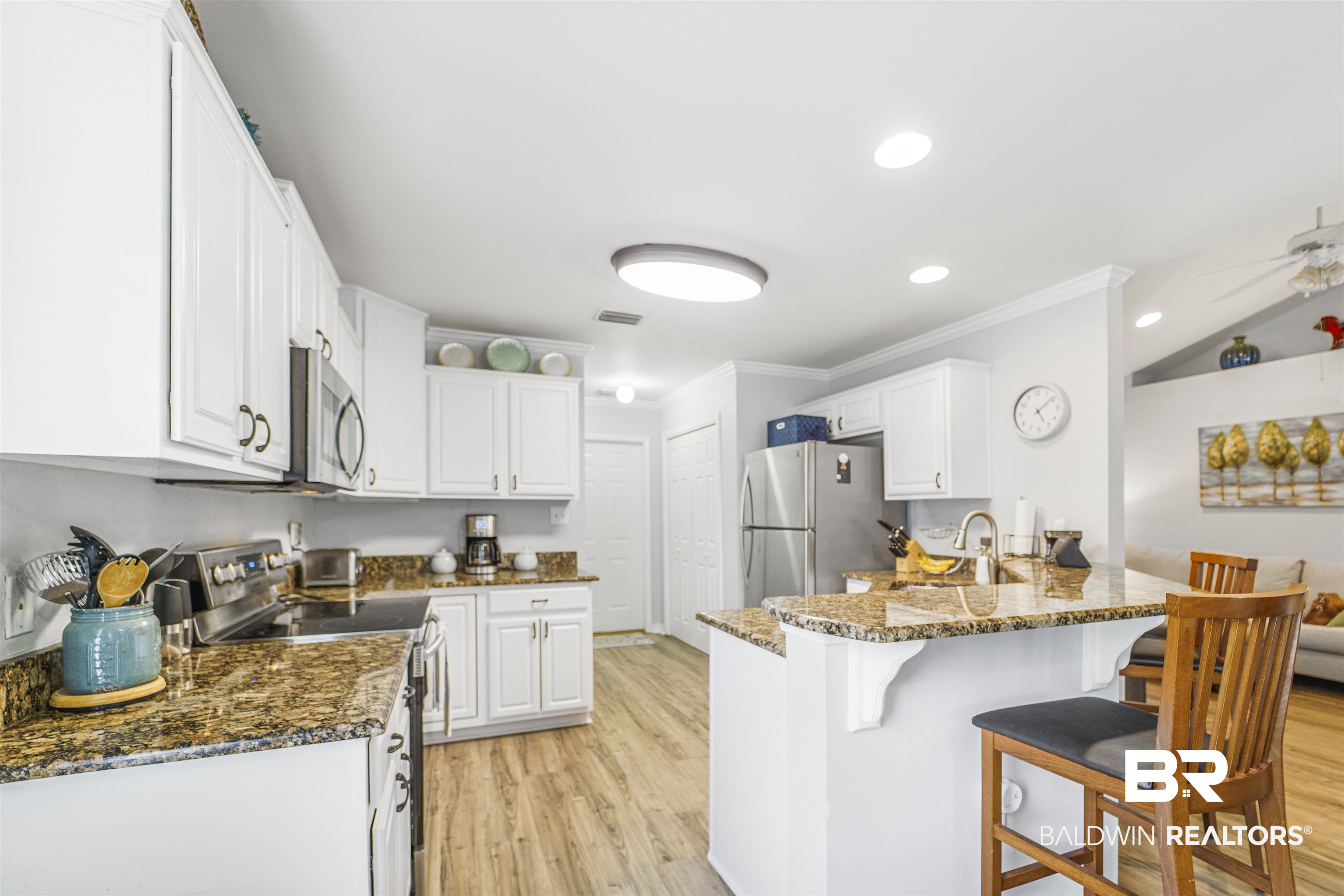 4620 Pine Boulevard Orange Beach, AL 36561 - Photo 11 of 49 Kitchen with stainless steel appliances, crown molding, a peninsula, light wood-style floors, and a breakfast bar