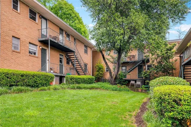 a brick building with a big yard plants and large trees