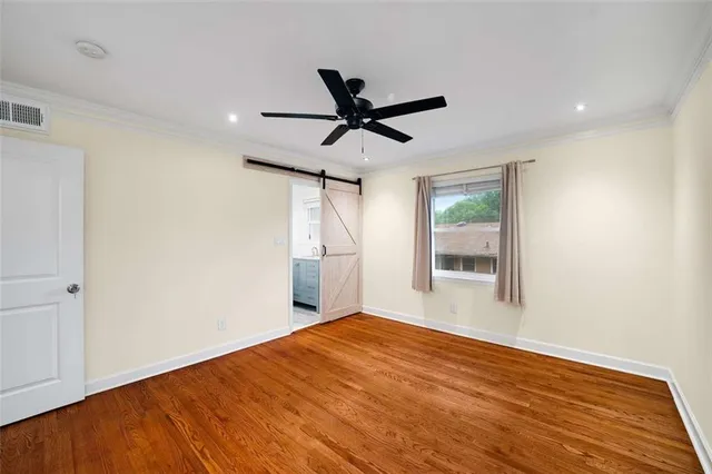 a view of empty room with wooden floor and fan