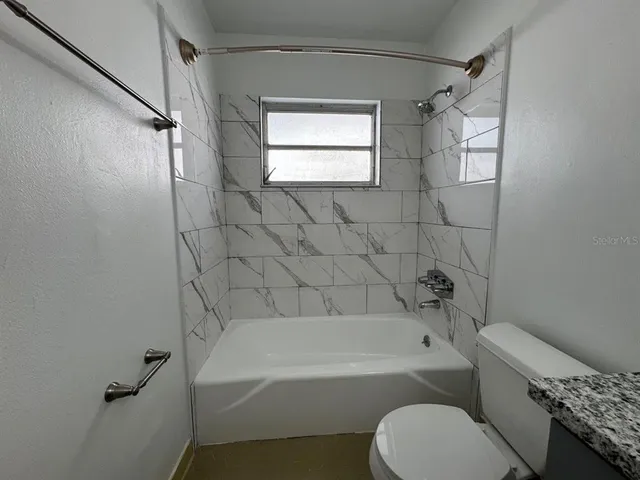 a bathroom with a granite countertop toilet a sink and bathtub