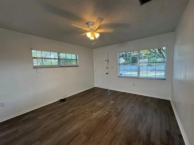 a view of empty room with wooden floor and fan