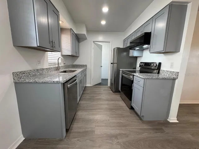 a kitchen with stainless steel appliances granite countertop a stove top oven a sink dishwasher a refrigerator and a microwave