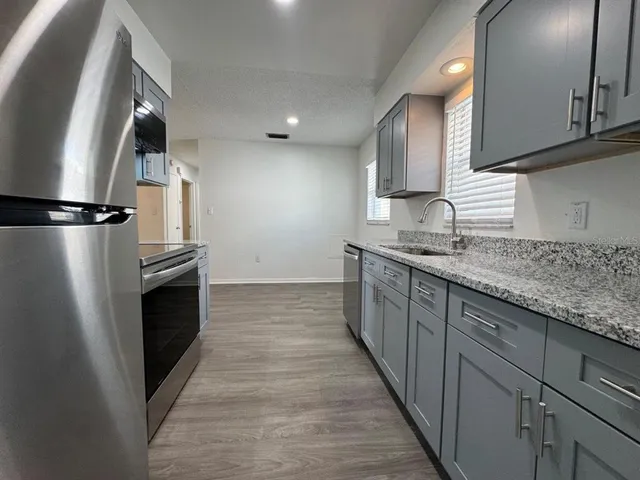 a kitchen with stainless steel appliances granite countertop a refrigerator a sink and a stove