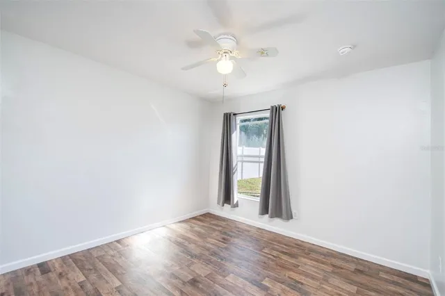 an empty room with wooden floor and a ceiling fan