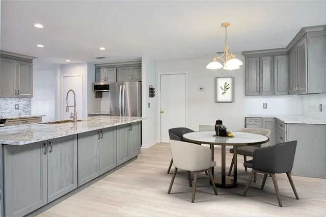 a kitchen with stainless steel appliances kitchen island granite countertop a sink a stove a table and chairs