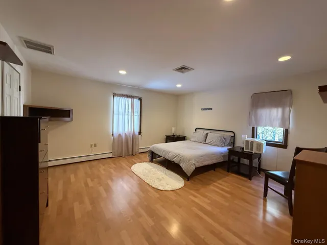 a spacious bedroom with a bed and wooden floor