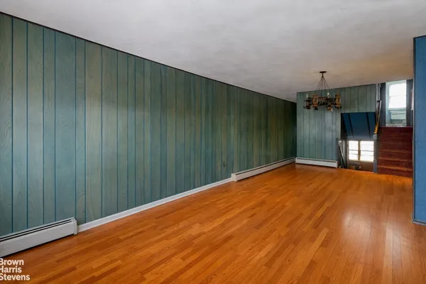 a view of a livingroom with wooden floor and stairs